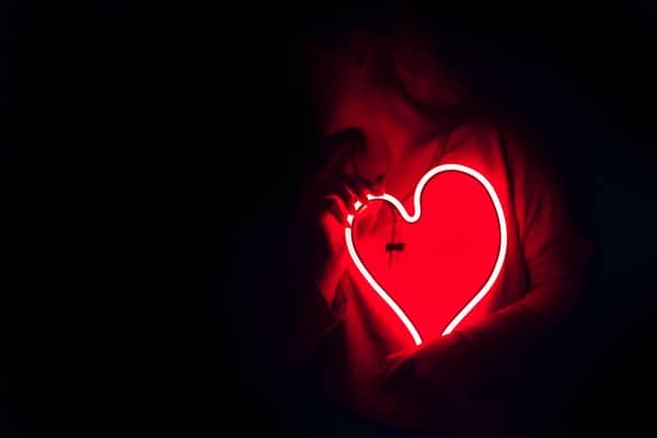 A person holding a neon heart