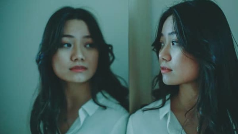 A woman looking at her reflection in a mirror.