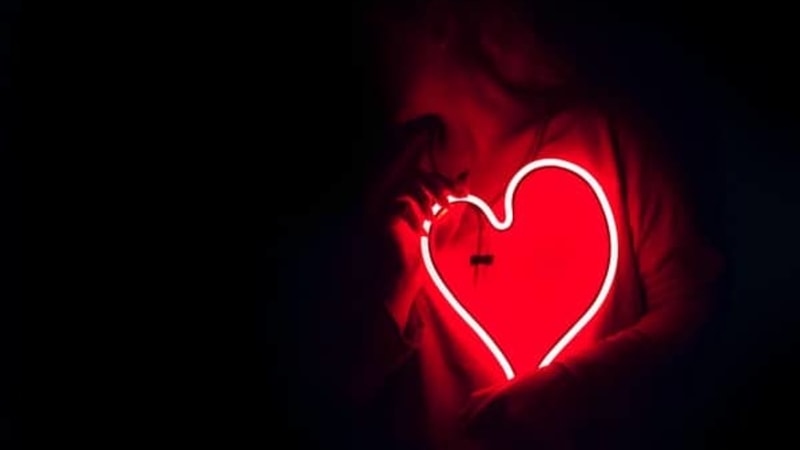 A person holding a neon heart
