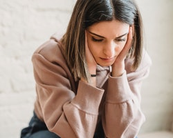 A young woman holding her head in her hands