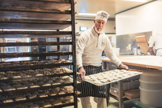 Baker stacking trays of butteries, Waas Bakery