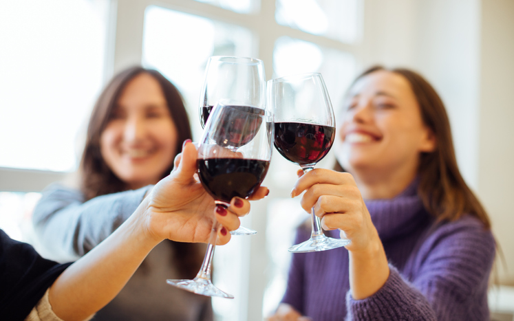 group of women clinking wine glasses