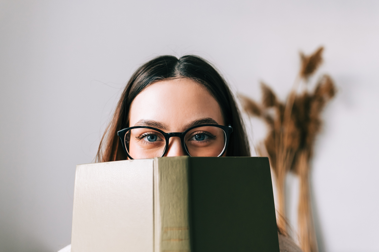 young woman hiding behind a book