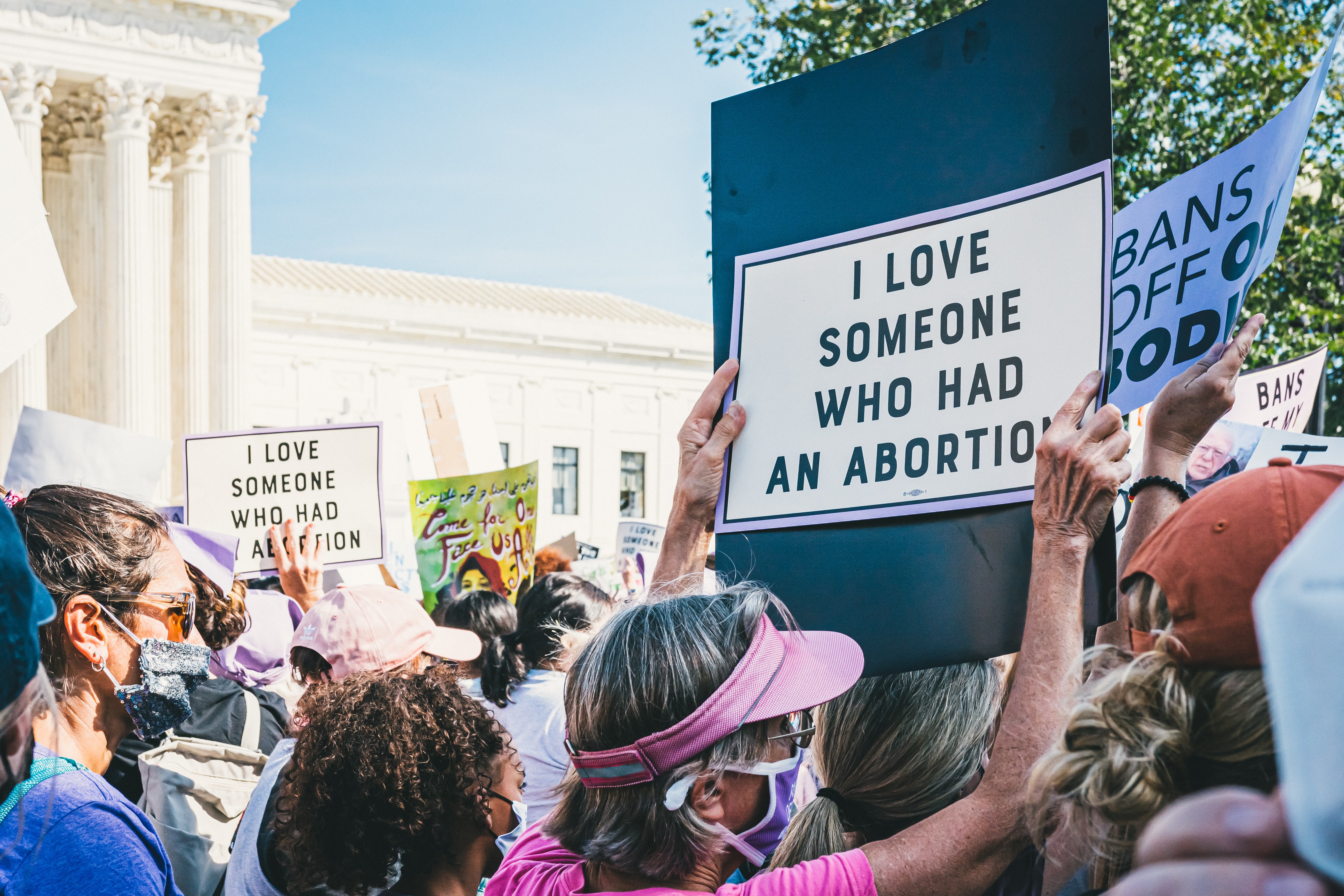 pro-choice protestors in front of the supreme court with sign that reads "i love someone who had an abortion"