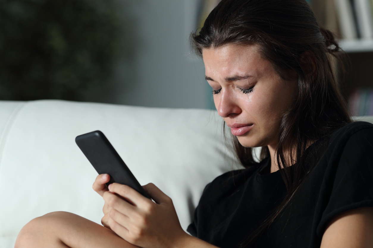 woman crying while using her mobile phone