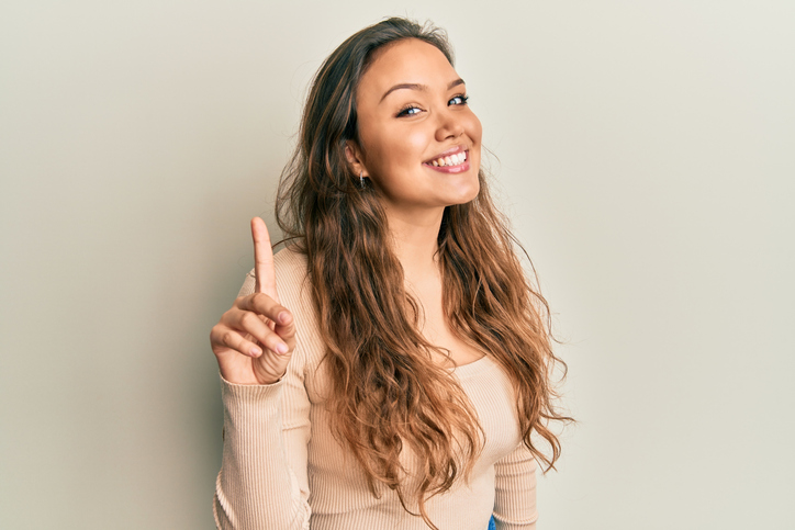 woman holding up one finger to represent transferring one embryo during ivf