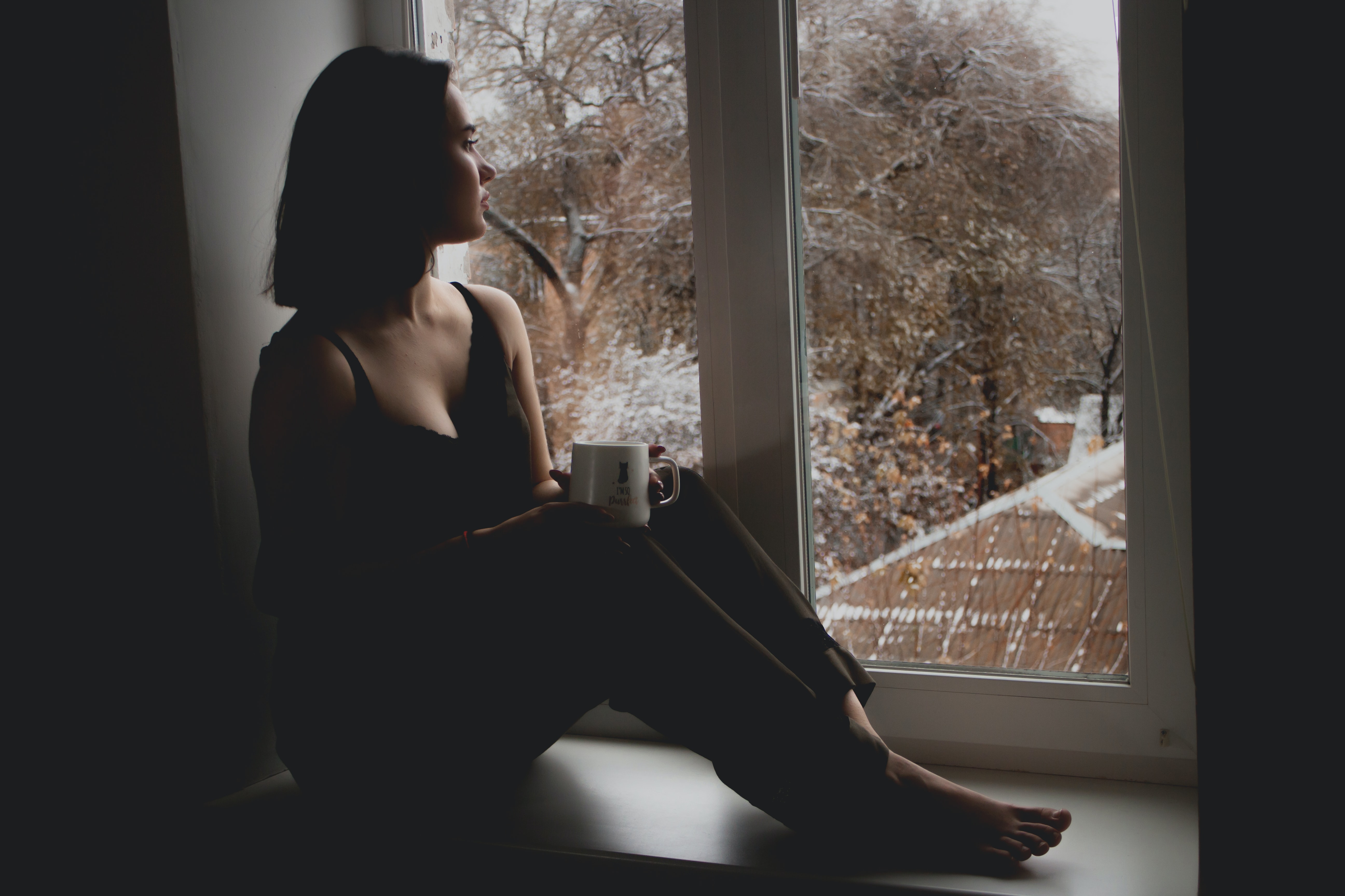 woman drinking tea and staring out the window