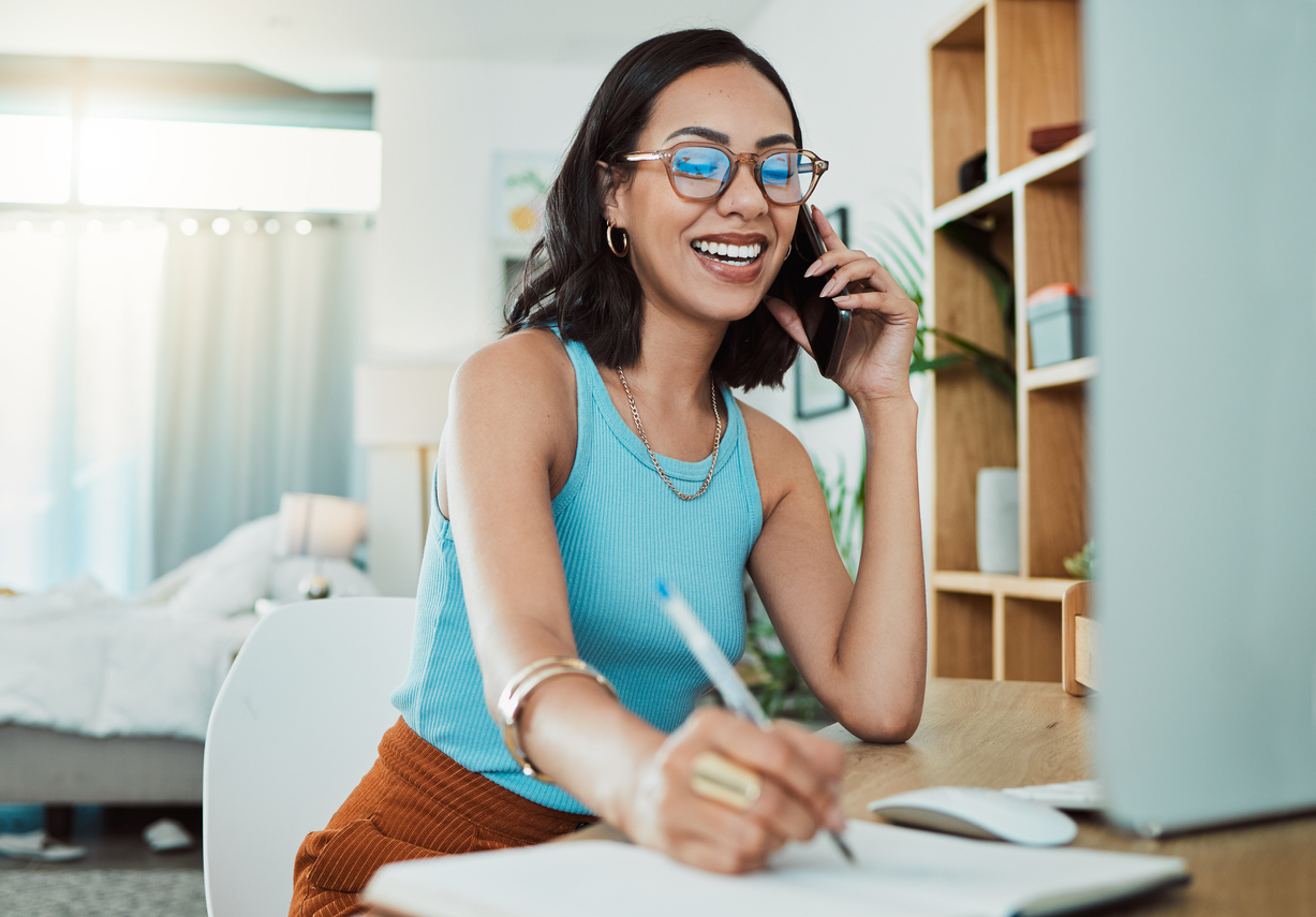 woman taking notes as she talks on the phone