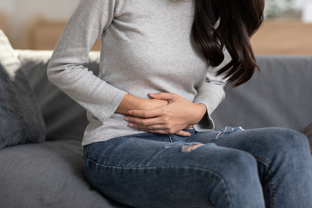 woman with ibs clutching her lower abdomen in pain