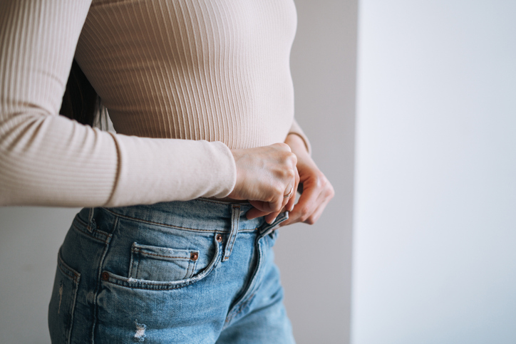 woman unbuttoning her jeans