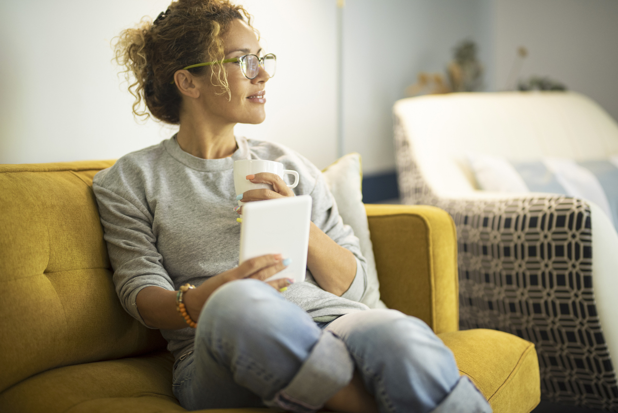 woman drinking coffee and reading on a tablet