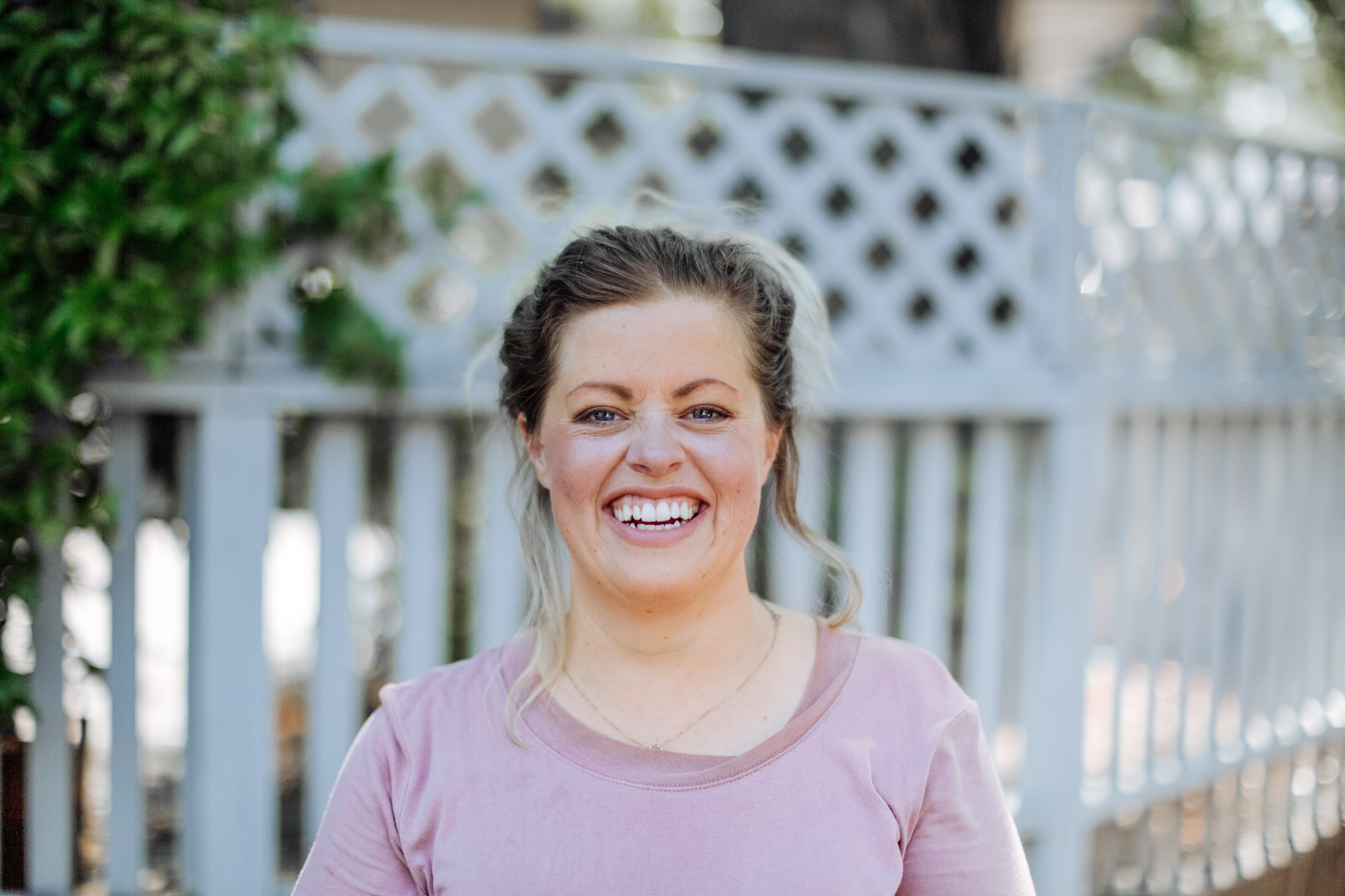 woman smiling in front of white picket fence