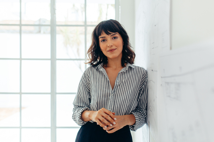 woman standing against a wall with a small smile on her face