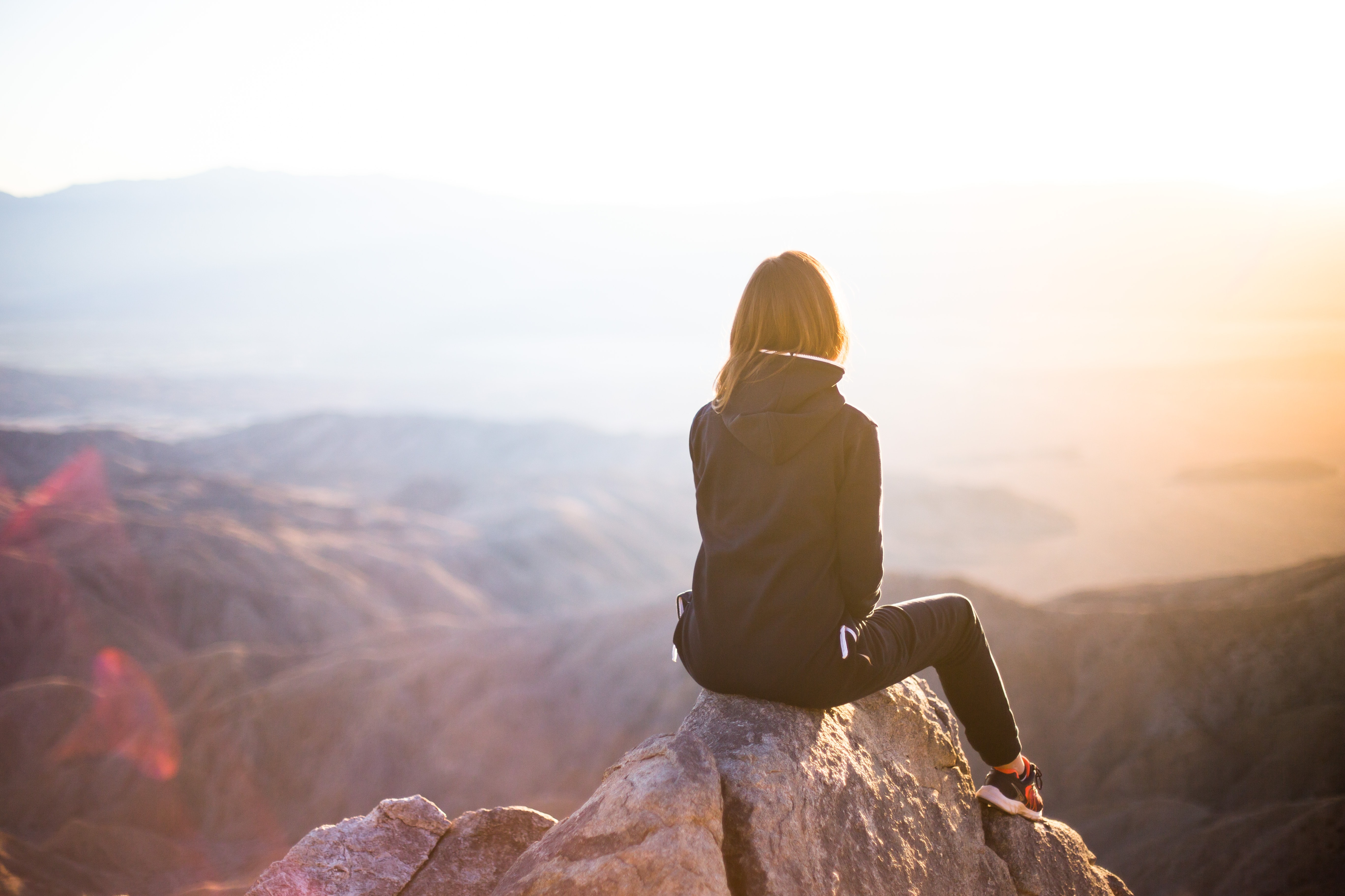 hiker watching the sun rise from the top of a mountain