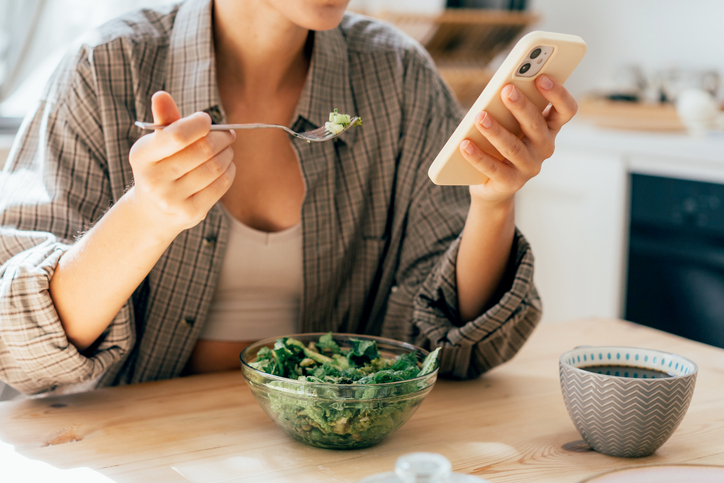 woman eating veggies and using a nutrient tracker app