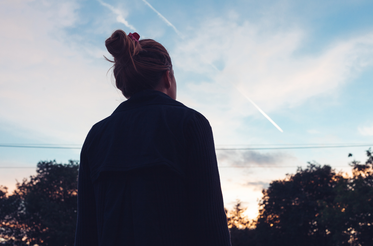 woman staring up at the sky as the sun sets