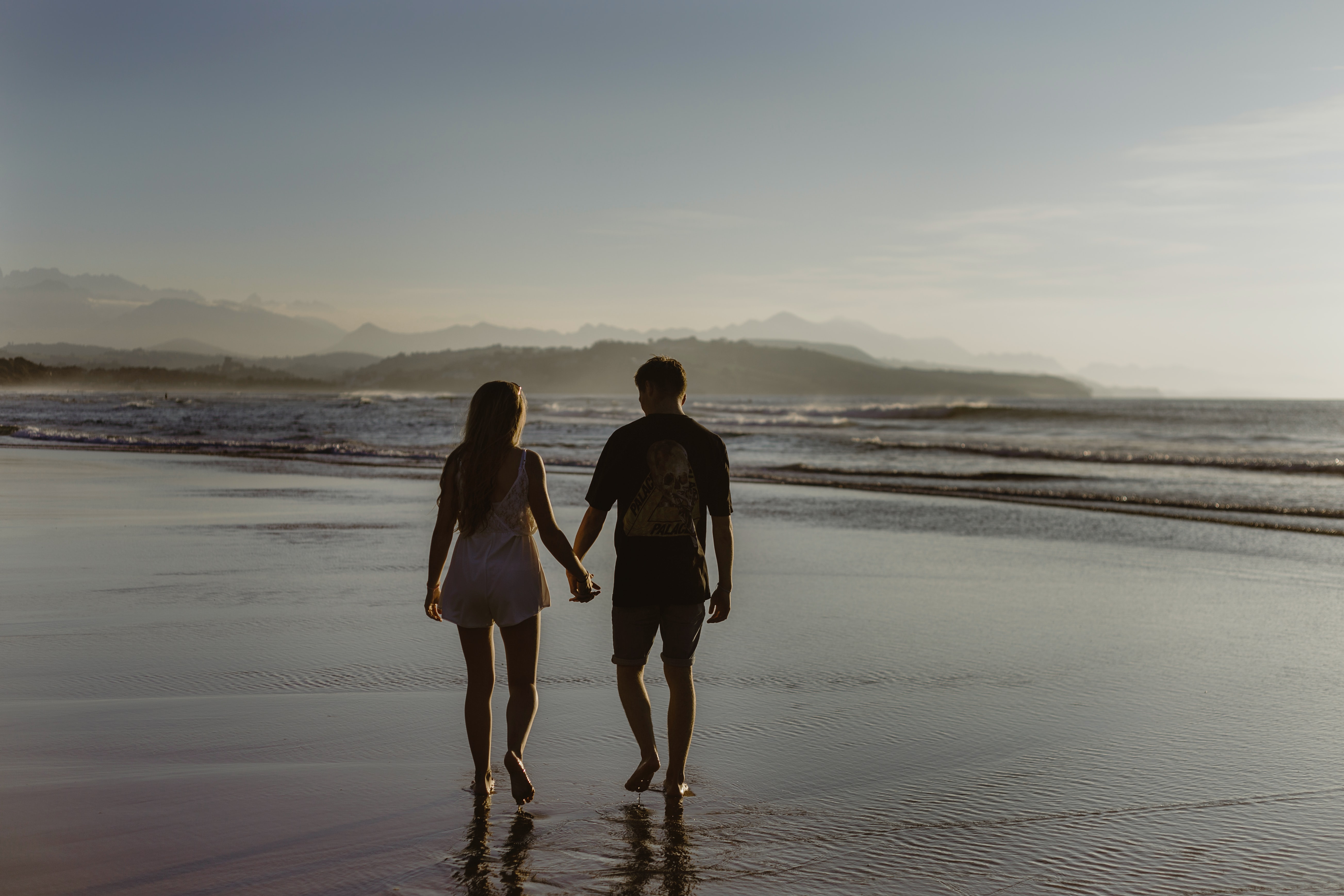 woman and man holding hands on the beach