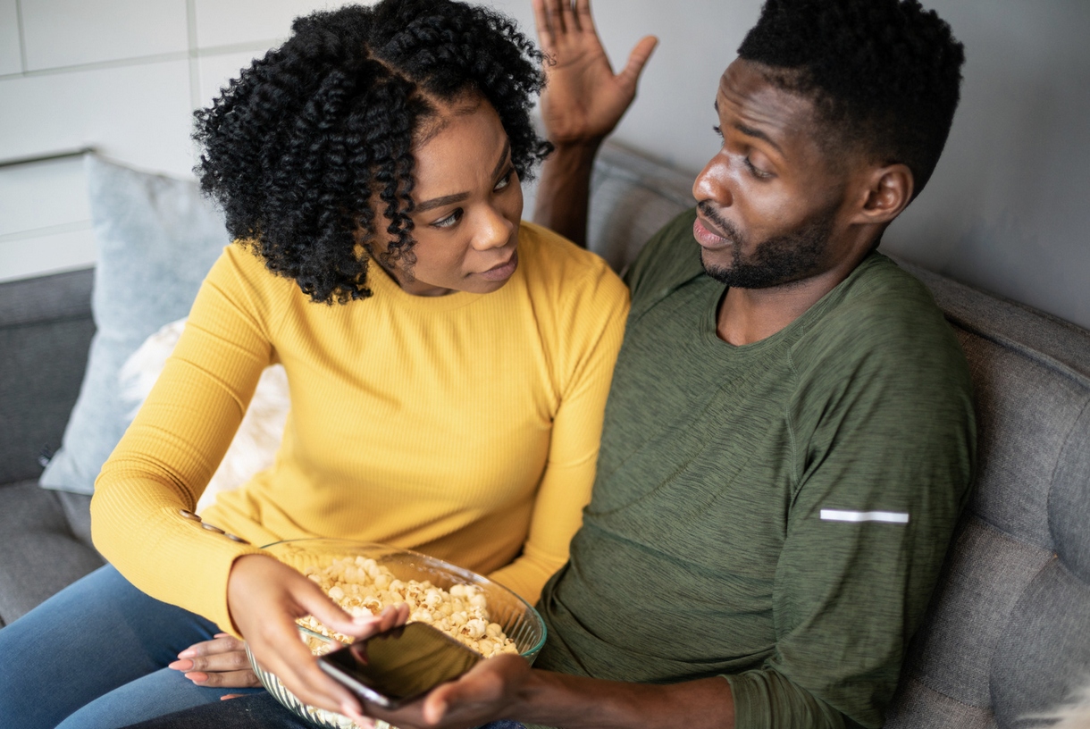 couple eating popcorn and looking at a mobile phone