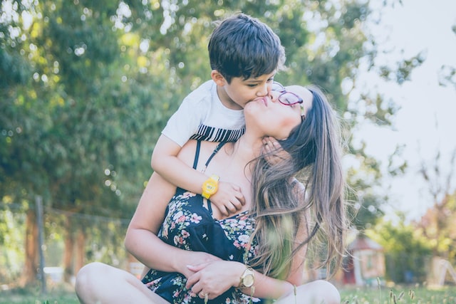 single mother by choice kissing her son in the park