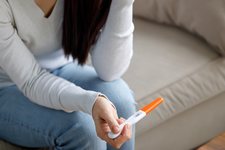 woman staring at her pregnancy test stick