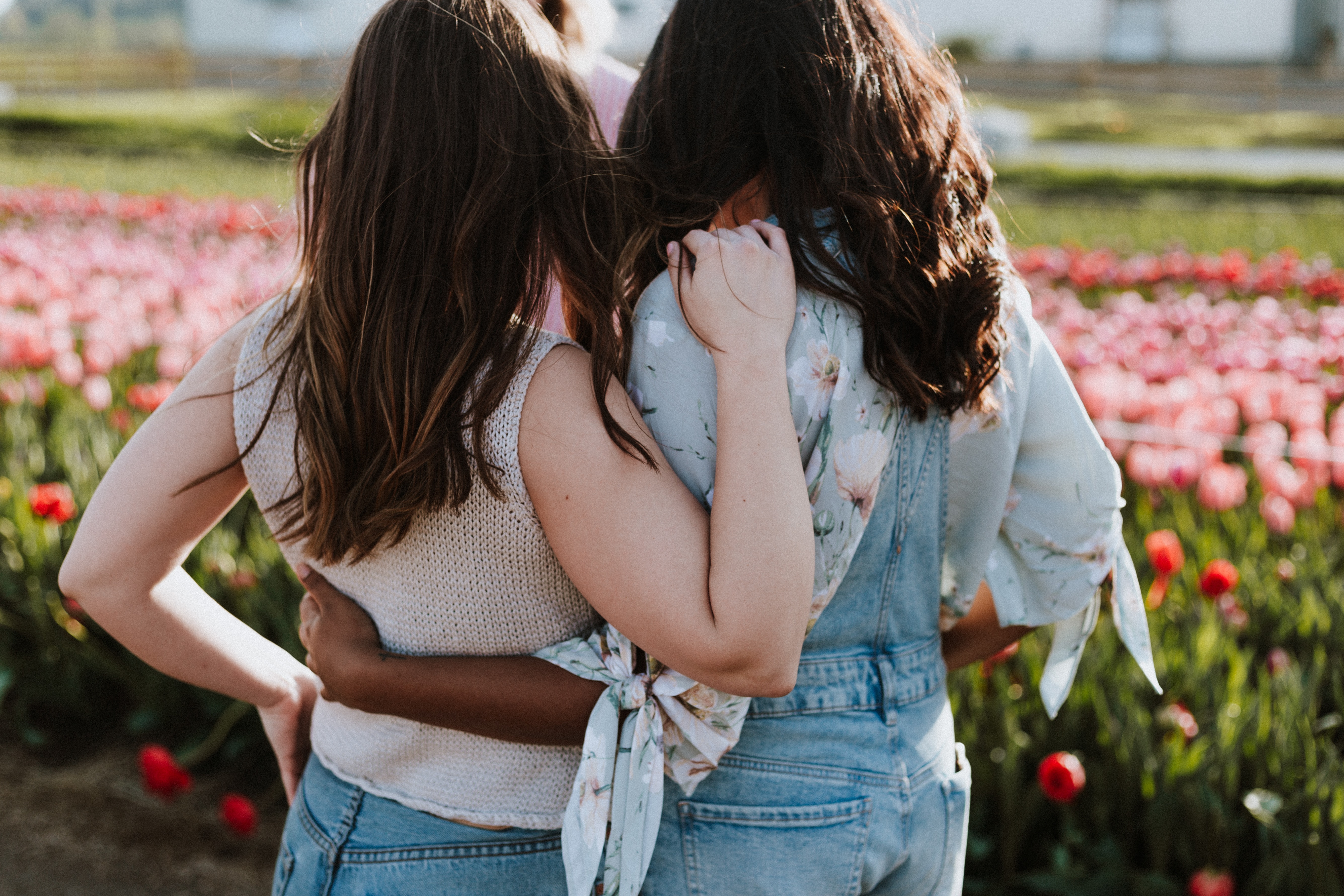 two women comforting each other near a field of flowers