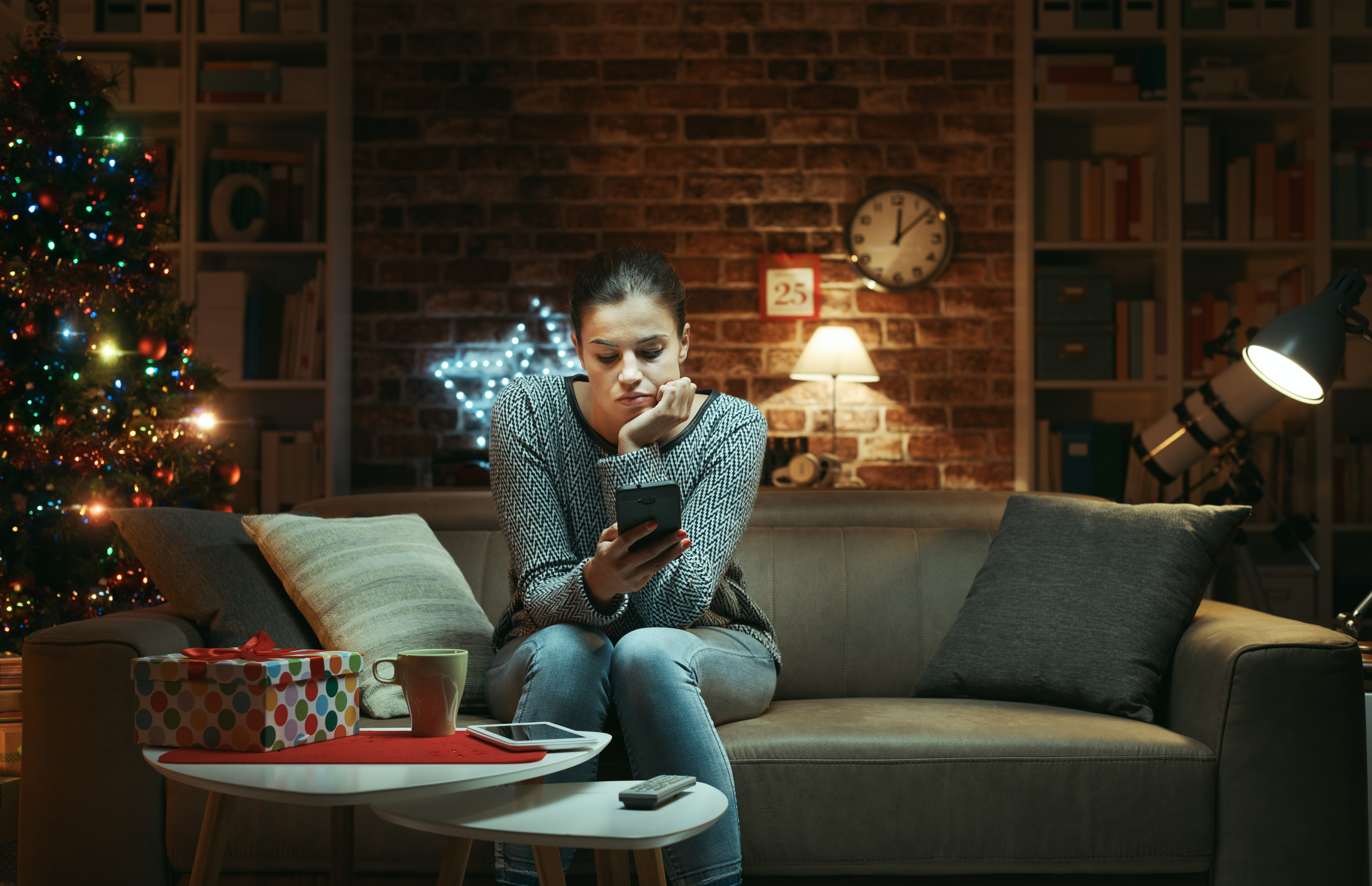 woman playing on a mobile phone in a living room full of christmas decor 