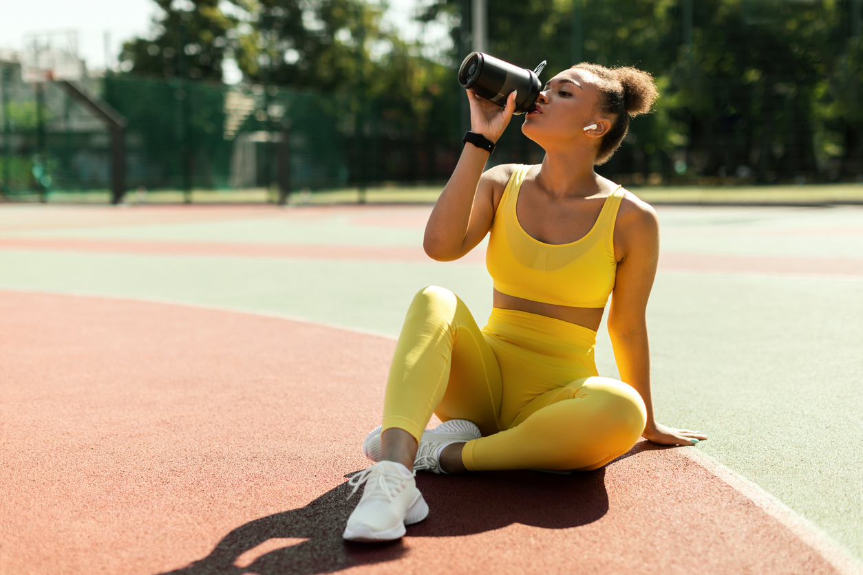 runner sitting on the track drinking water