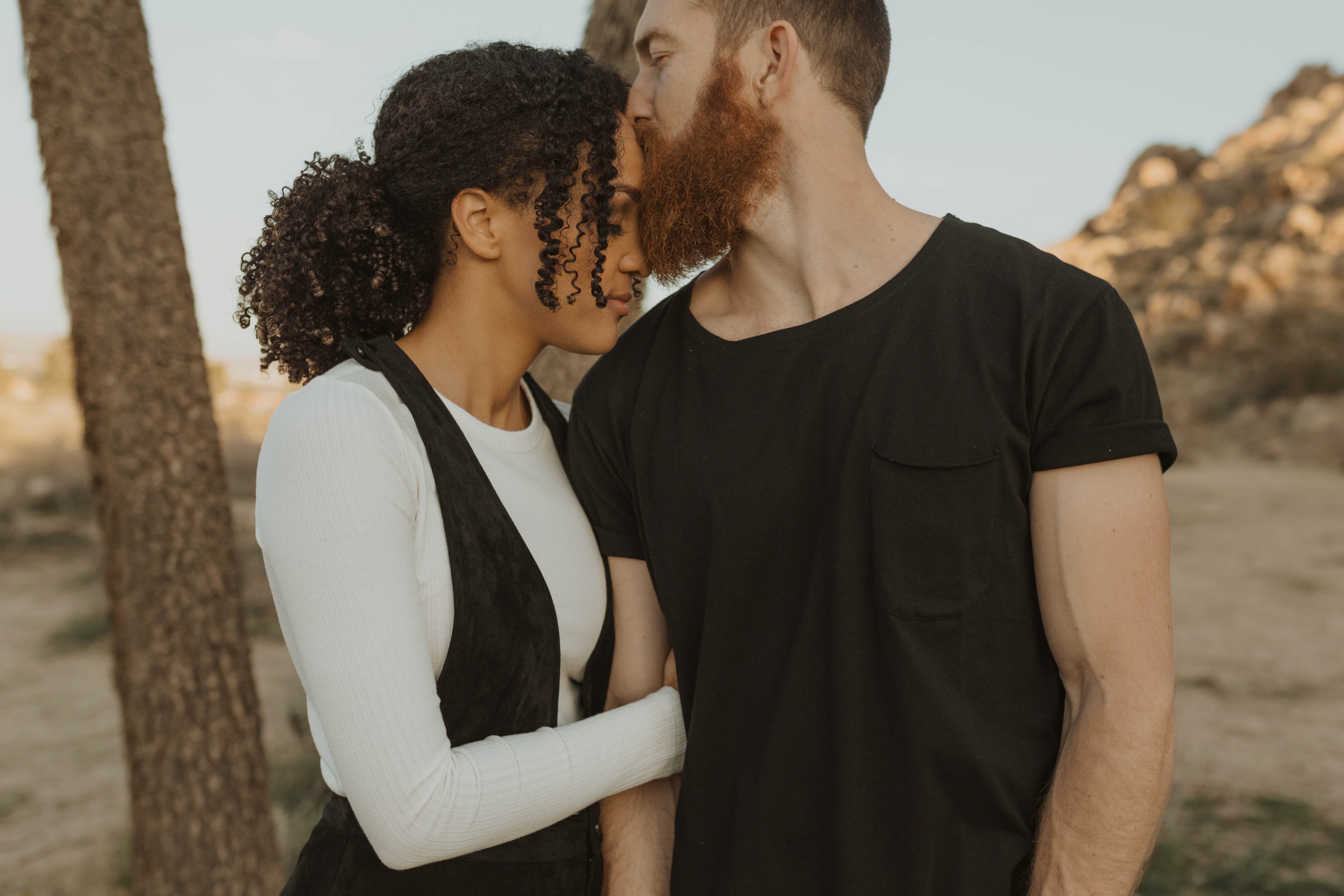 man kissing woman on the forehead