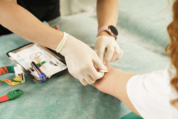 phlebotomist putting a bandage on a patient after a blood draw