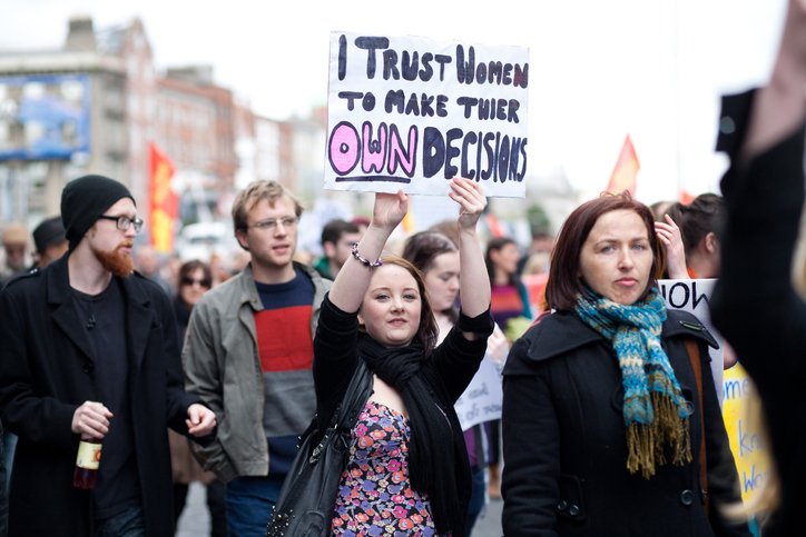 reproductive rights activist holding a sign that reads "i trust women to make their own decisions"