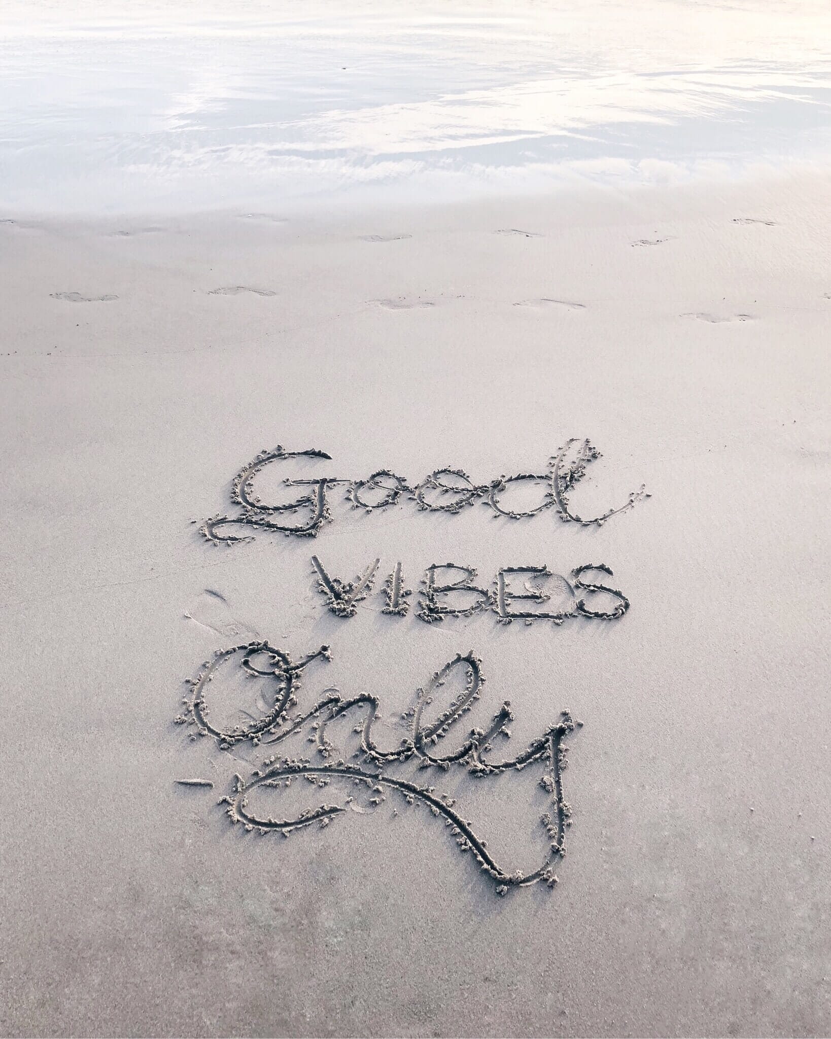 writing in the sand that reads good vibes only