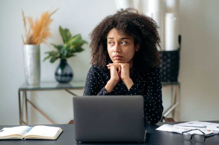 woman in front of a computer gazing out a window