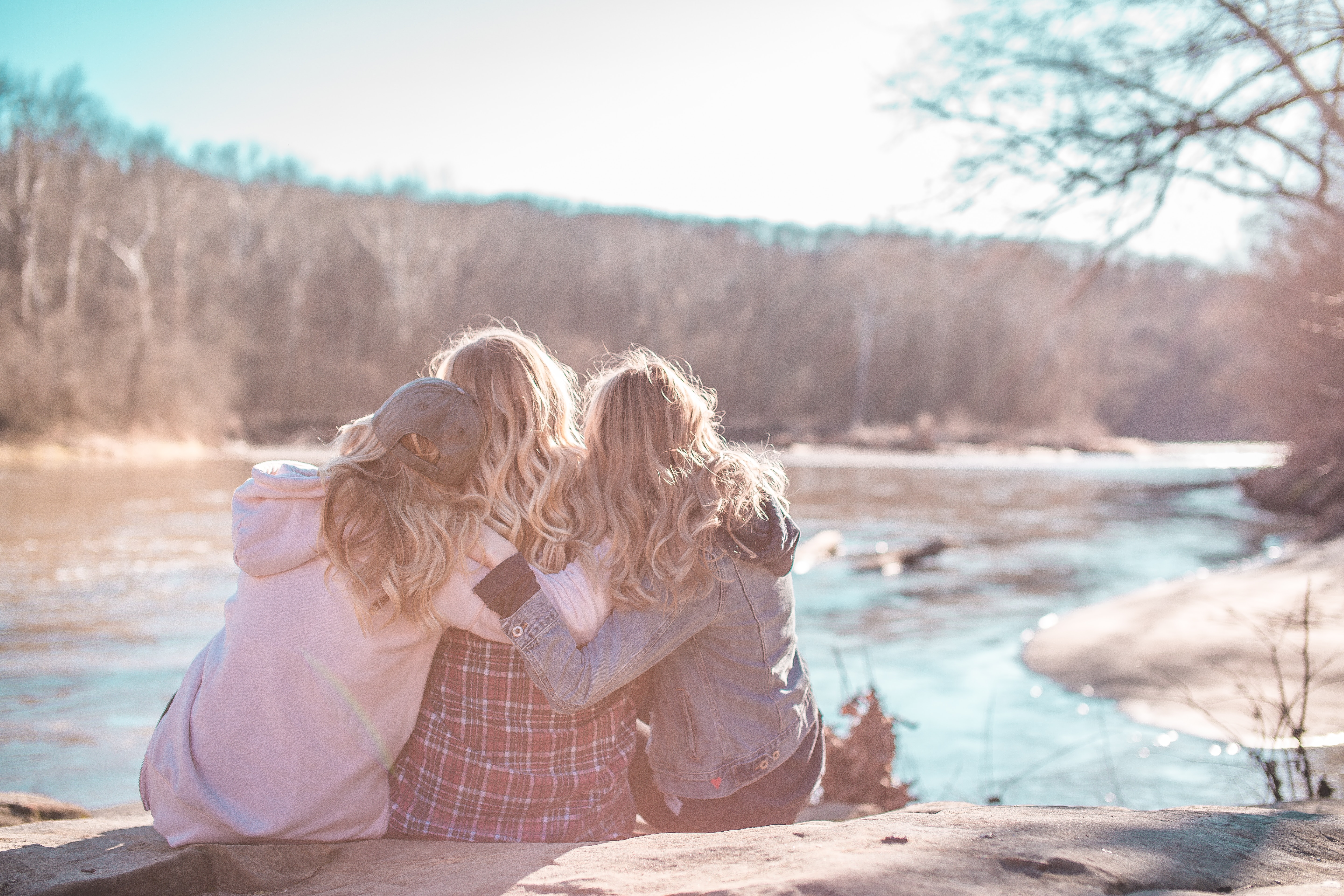 two women comforting a friend in distress near a river