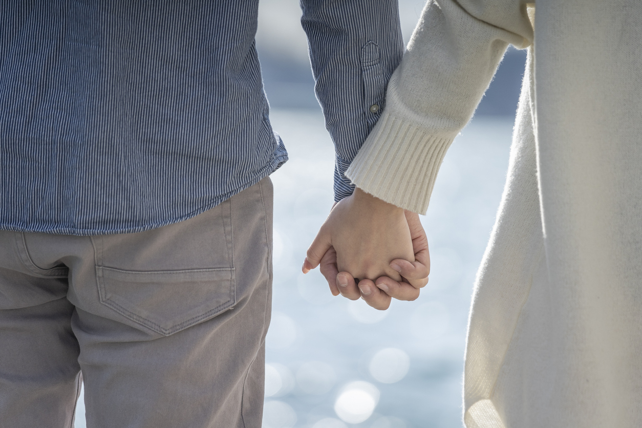 couple holding hands by the water