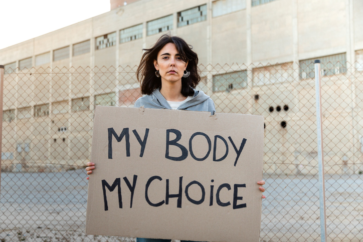 reproductive rights activist holding a sign that reads "my body my choice"