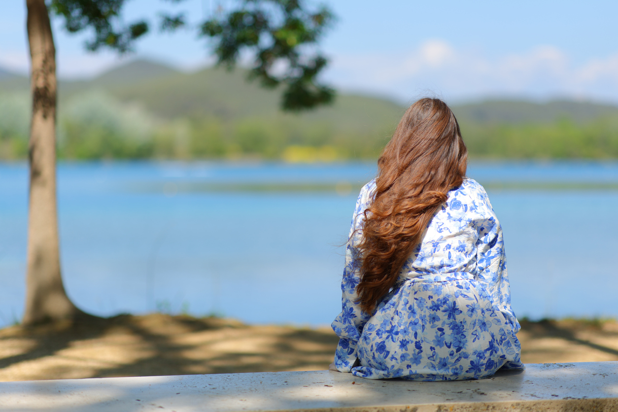 woman sitting alone near a lake