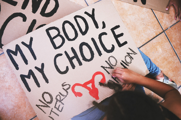 woman creating a my body my choice sign