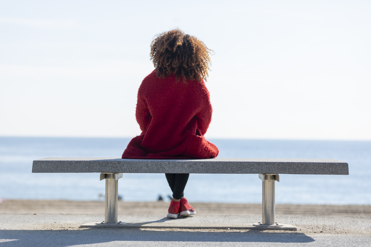 woman sitting on a bench near the ocean