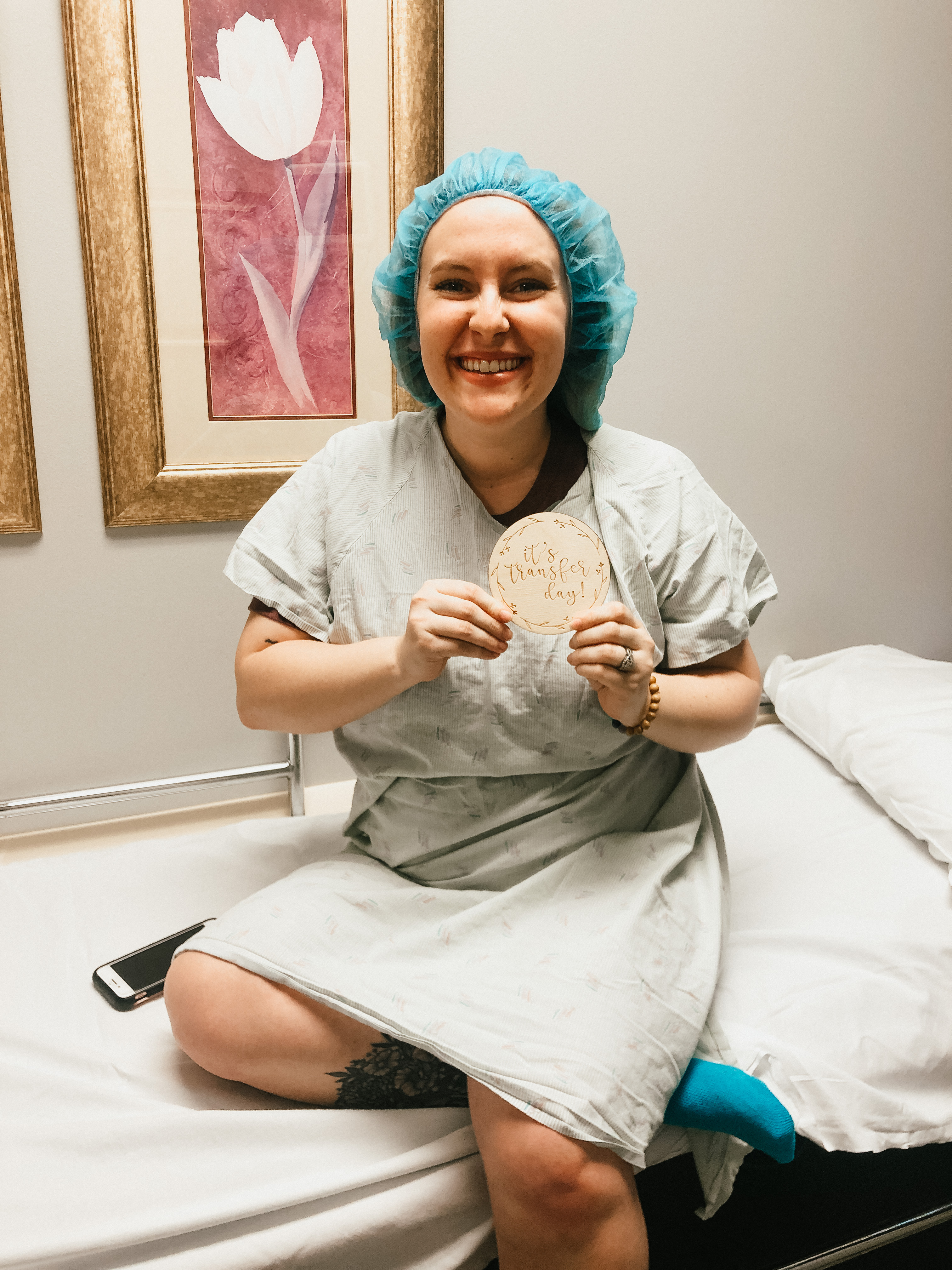 kayla kohl in the fertility clinic holding a sign that says &quot;It is transfer day!&quot;