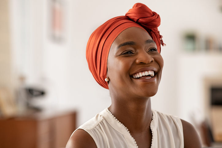 woman wearing a orange head wrap and smiling