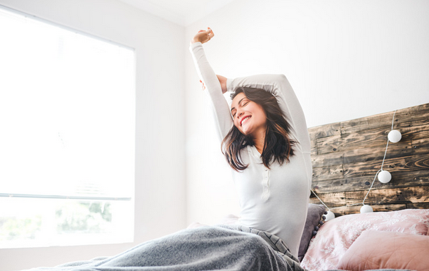 well-rested woman stretching in bed