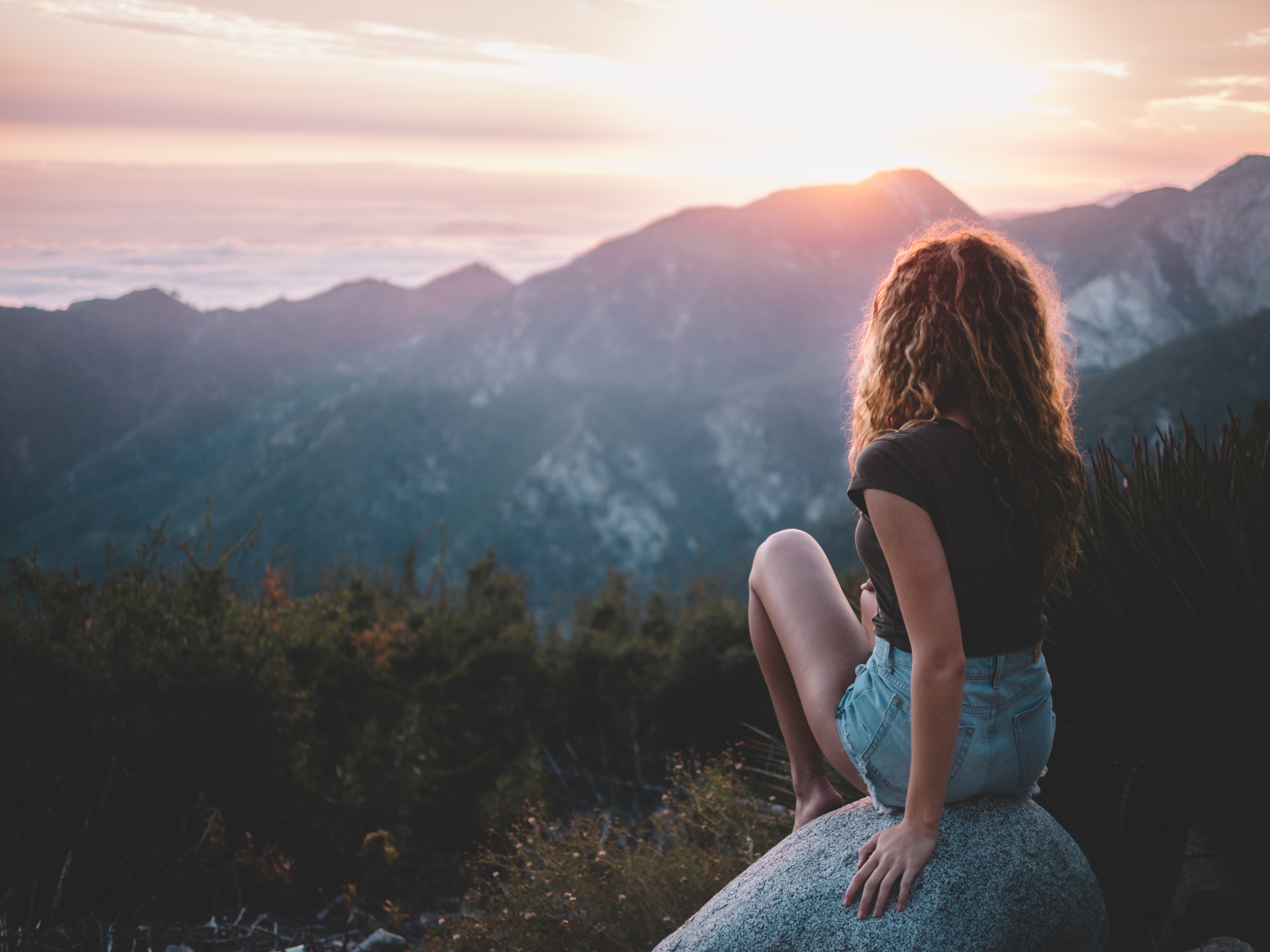 woman watching the sun set behind a mountain