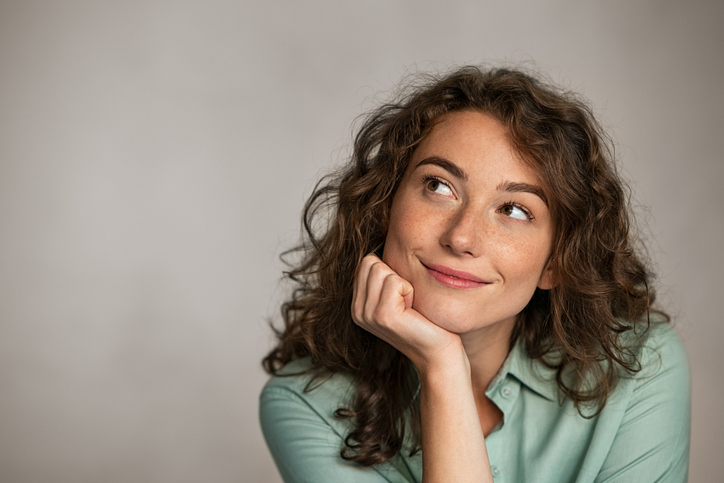 woman resting her head in her hand contemplating if she should transfer one or two embryos