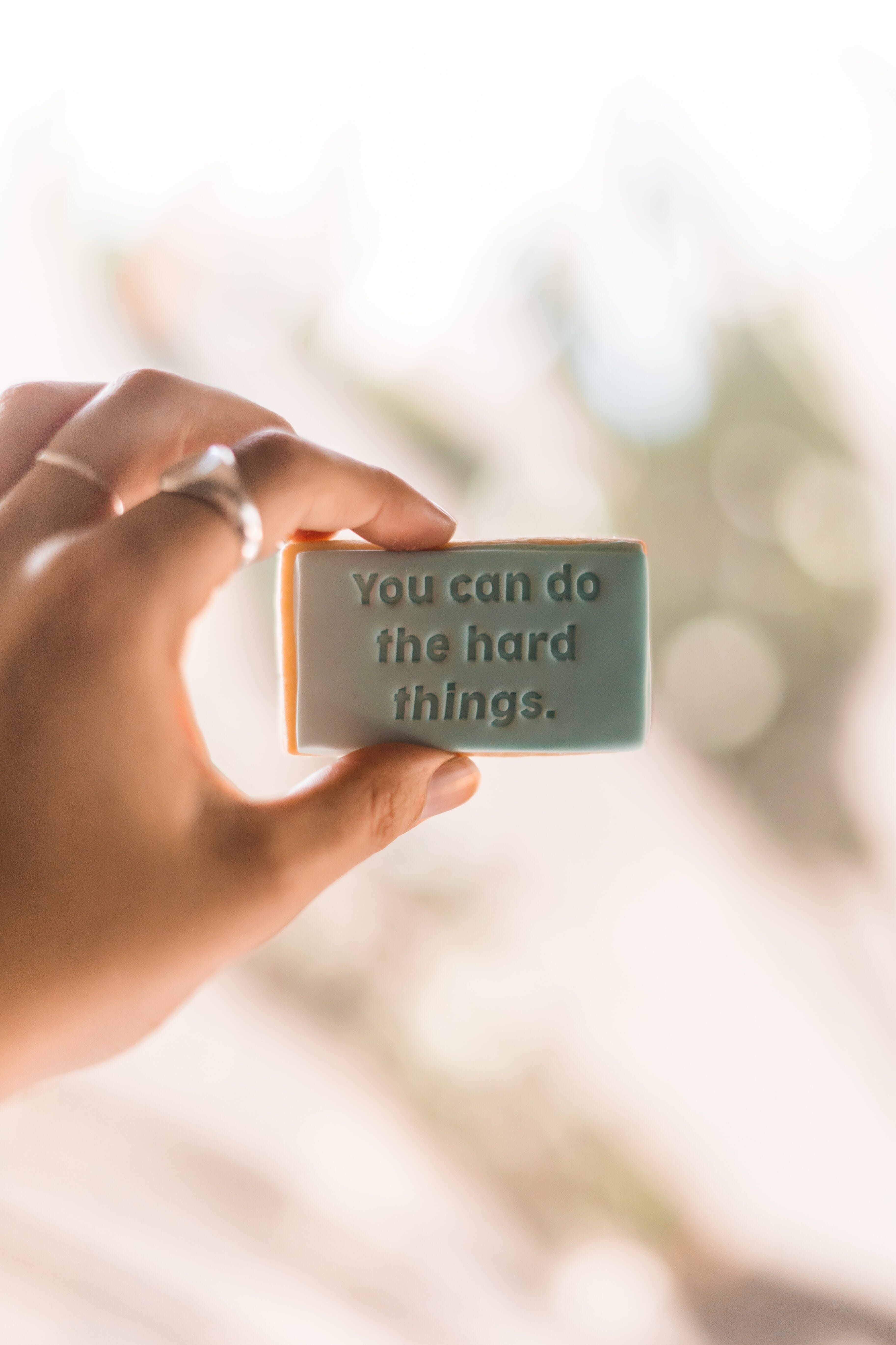 woman holding object that reads you can do the hard things