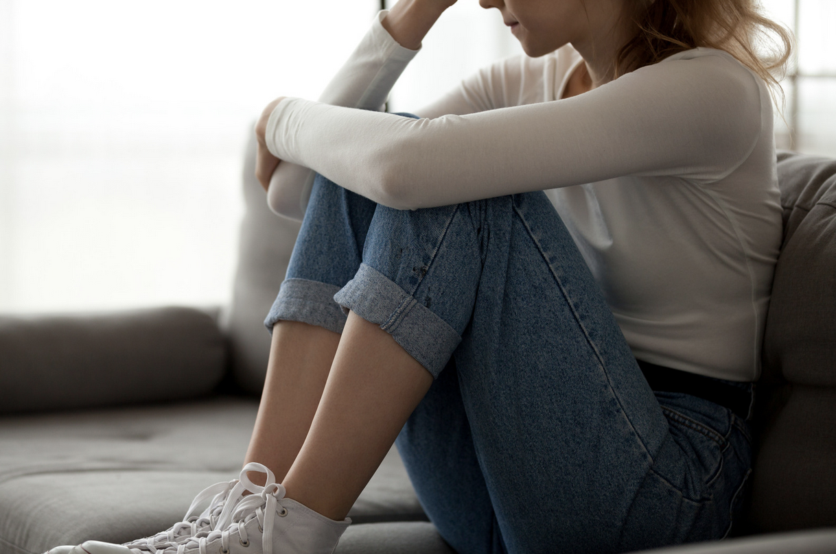 distraught woman sitting with knees tucked in to her body