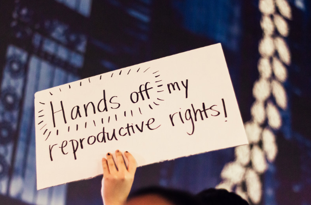 woman holding sign that reads "hands off my reproductive rights"