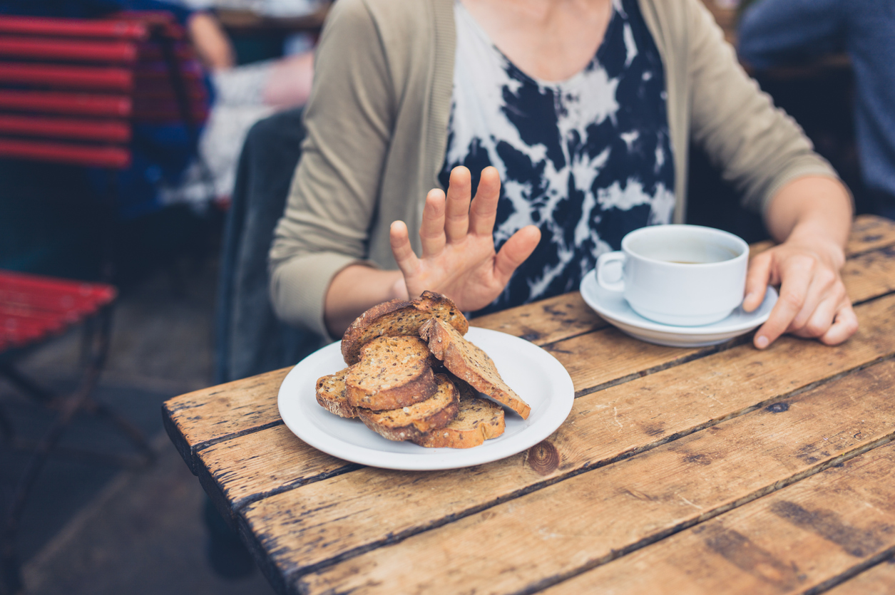 woman with Celiac disease saying no to a plate of toast