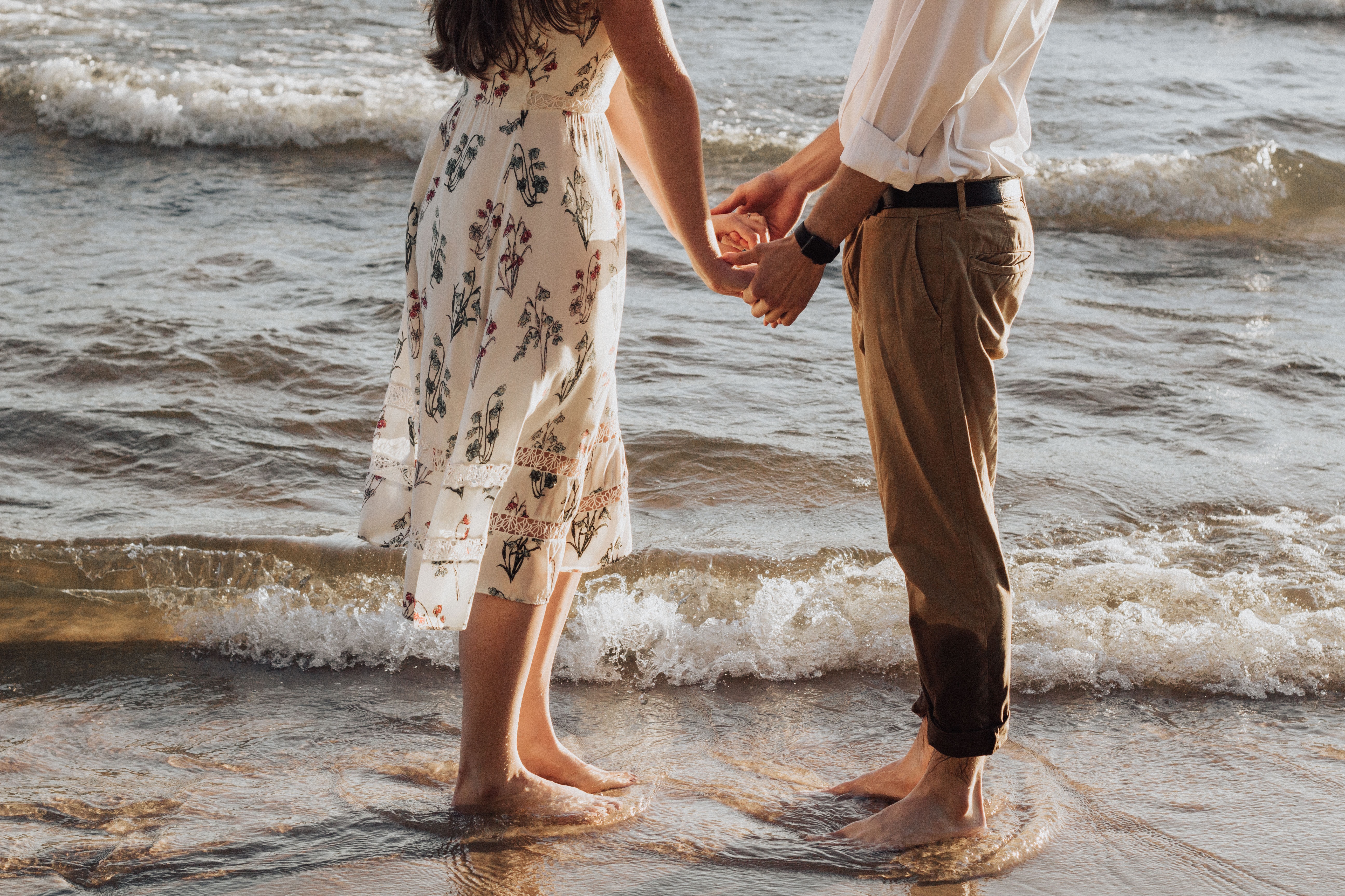 woman and man holding hands at the beach