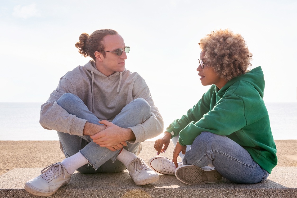 man and woman sitting cross-legged on a sea wall