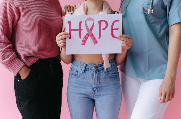 three women holding a breast cancer awareness sign that reads "hope"